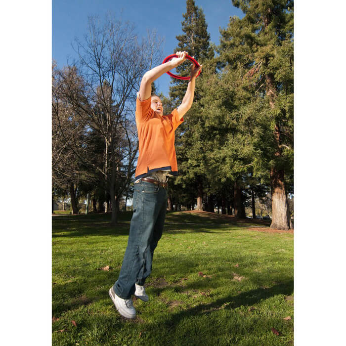 Aerobie - Junge fängt orangen Ring im Sprung Aerobie - Junge fängt orangen Ring im Sprung